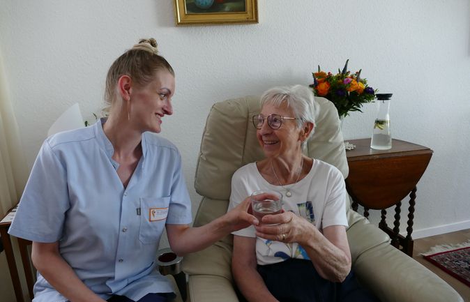 Eine Pflegefachkraft beim Hausbesuch mit einer alten Dame